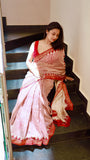 Model wearing a Titafu Maheshwari Silk Saree with red horizontal stripes, a cream base, and traditional triangle borders on a staircase.