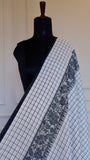 Detail view of the monochrome check pattern and woven border of a
Dhonekhali saree.