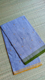 Close-up of folded Dhonekhali saree on a grass mat showcasing the authentic texture and dual-colored handloom borders.