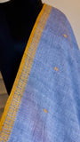 Extreme close-up of the ochre yellow border and intricate thread work on a steel blue Bengal handloom cotton saree.