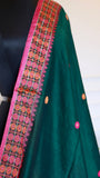 A macro detail shot focusing on the crisp, vibrant borders of the Baluchari Cotton Saree, showcasing the precision of the pink and orange circular check patterns woven into the fabric edge.