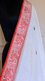 Close-up details of the red threadwork border on an off-white Baluchari Cotton Saree, showcasing the artisanal hand-knotted fringe finishes.