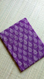 Neat flat-lay fold of the premium purple cotton fabric on a woven mat, showcasing the dense, uniform leaf-cluster handblock prints.