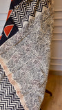 Close-up of cream and black floral paisley handblock print on a Maheshwari silk saree pallu with a gold zari border.