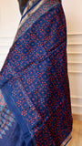 Close-up drape of Titafu's Indigo Maheshwari silk saree showing red geometric handblock prints and a fine gold zari border.
