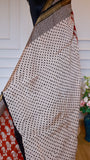Close-up of cream body with black polka dots on a Maheshwari handblock printed silk saree with gold zari border.