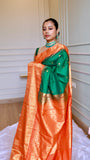 Side pose showing the rich contrast orange pallu and temple border details on the bottle green semi Gadwal saree.