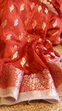 Close-up detail shot showcasing the fine silver zari floral border weave and paisley motifs on the soft crimson red georgette fabric.