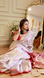 Side profile view of a model wearing an off-white georgette saree with a metallic red blouse and gold jewelry.