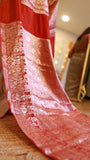 Extreme close-up of the fine silver and gold zari floral pattern along the red pallu of a Banarasi georgette saree.