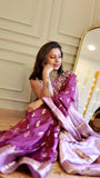 Woman sitting comfortably wearing a deep purple georgette Banarasi saree paired with a statement silver choker necklace.