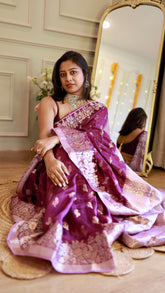 Front-facing shot of a model seated, showcasing the rich silver zari border details of the purple Banarasi saree.