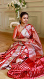 Model seated on the floor demonstrating the drape and detailed pallu motifs of the crimson Munga contrast Banarasi silk saree.