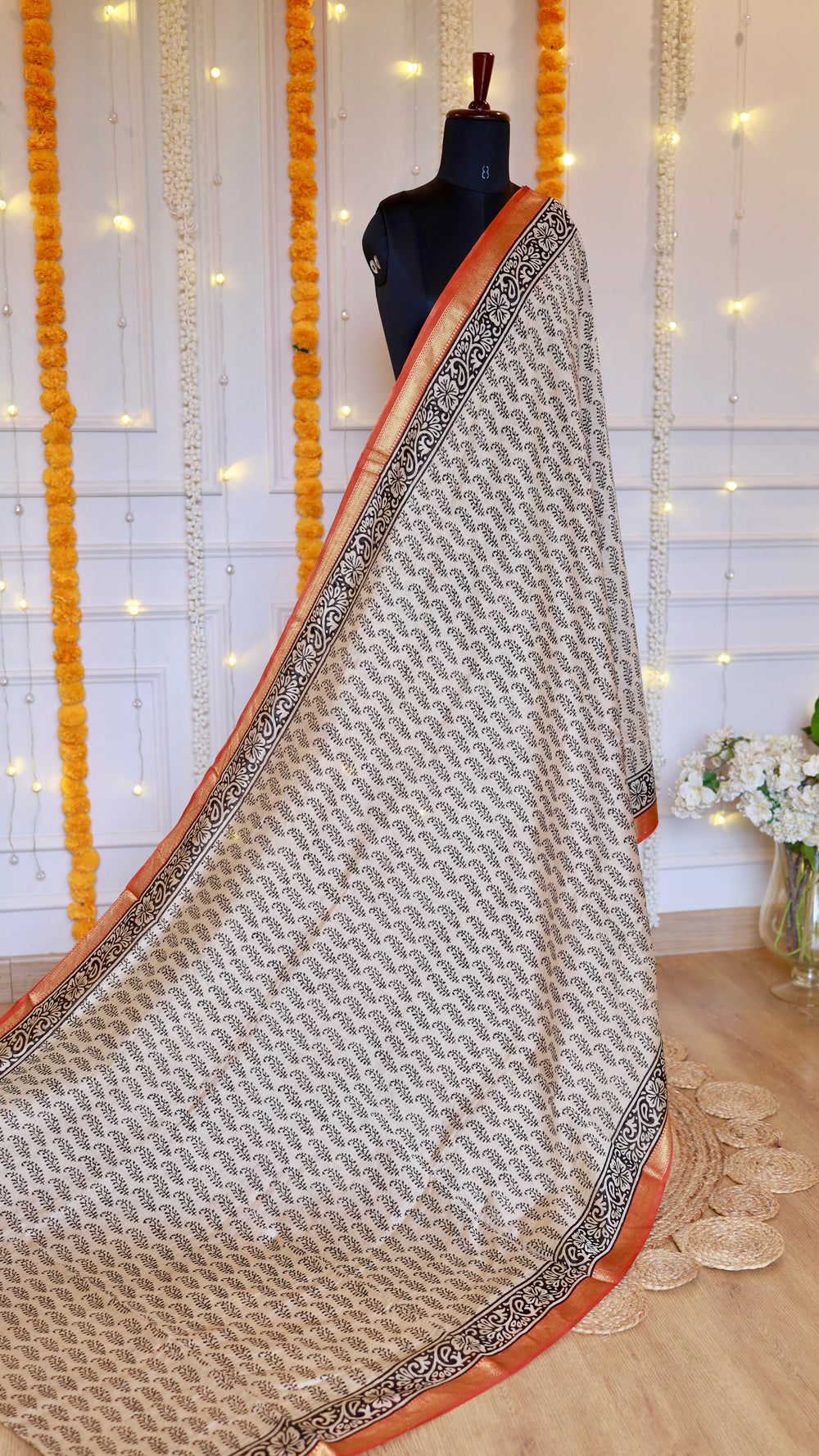 Full mannequin drape of off-white and black block-printed Maheshwari silk saree with rust red zari border