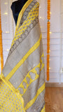 Yellow handblock printed Maheshwari silk saree drape showing geometric striped pallu and black floral woven zari border