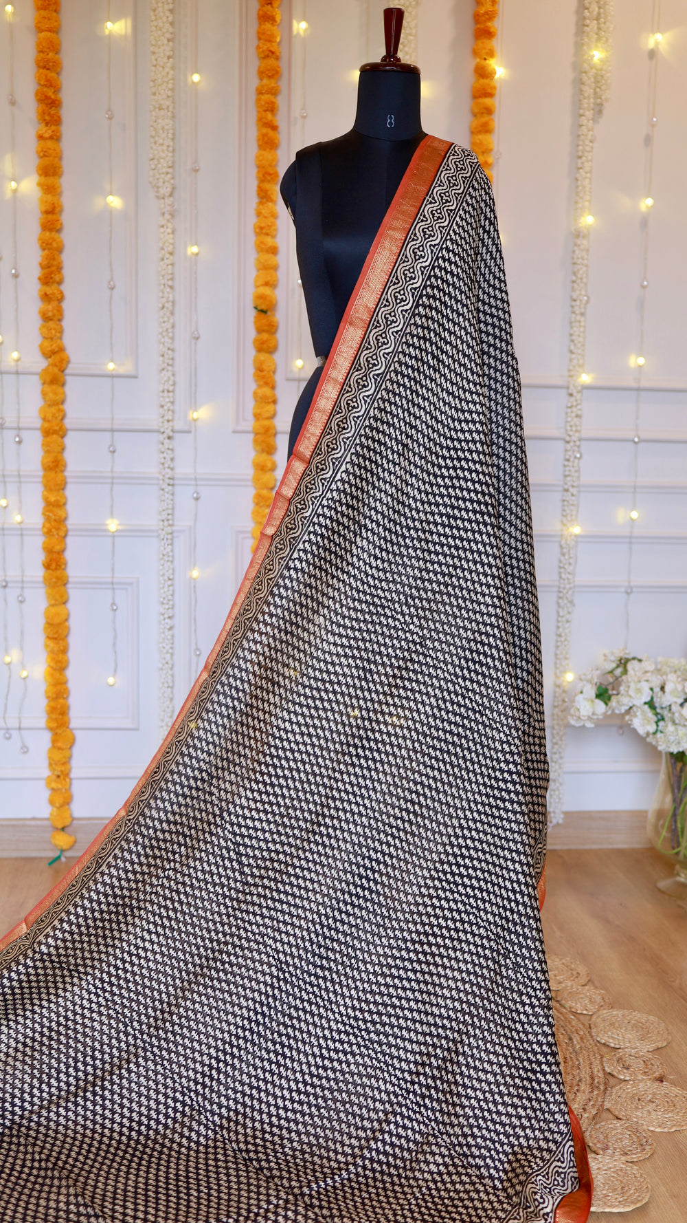 Full drape view of black and off-white geometric hand-block printed Maheshwari silk saree on mannequin with rust orange zari border