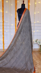 Full drape view of black and off-white geometric hand-block printed Maheshwari silk saree on mannequin with rust orange zari border