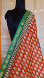 Close-up view of Rust Red Maheshwari Silk Saree featuring white leaf block prints and emerald green zari border.
