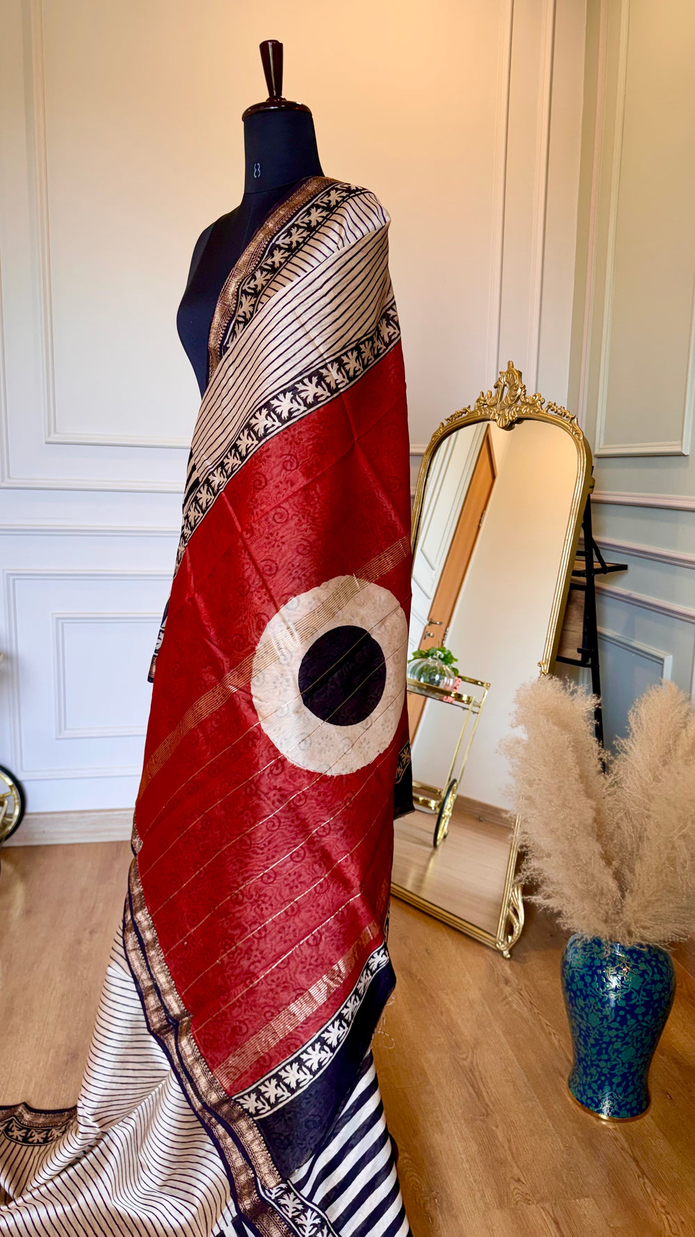 High-contrast shot of the deep red pallu featuring gold Zari stripes and a white circular block-print motif.