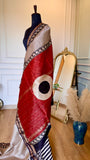 High-contrast shot of the deep red pallu featuring gold Zari stripes and a white circular block-print motif.