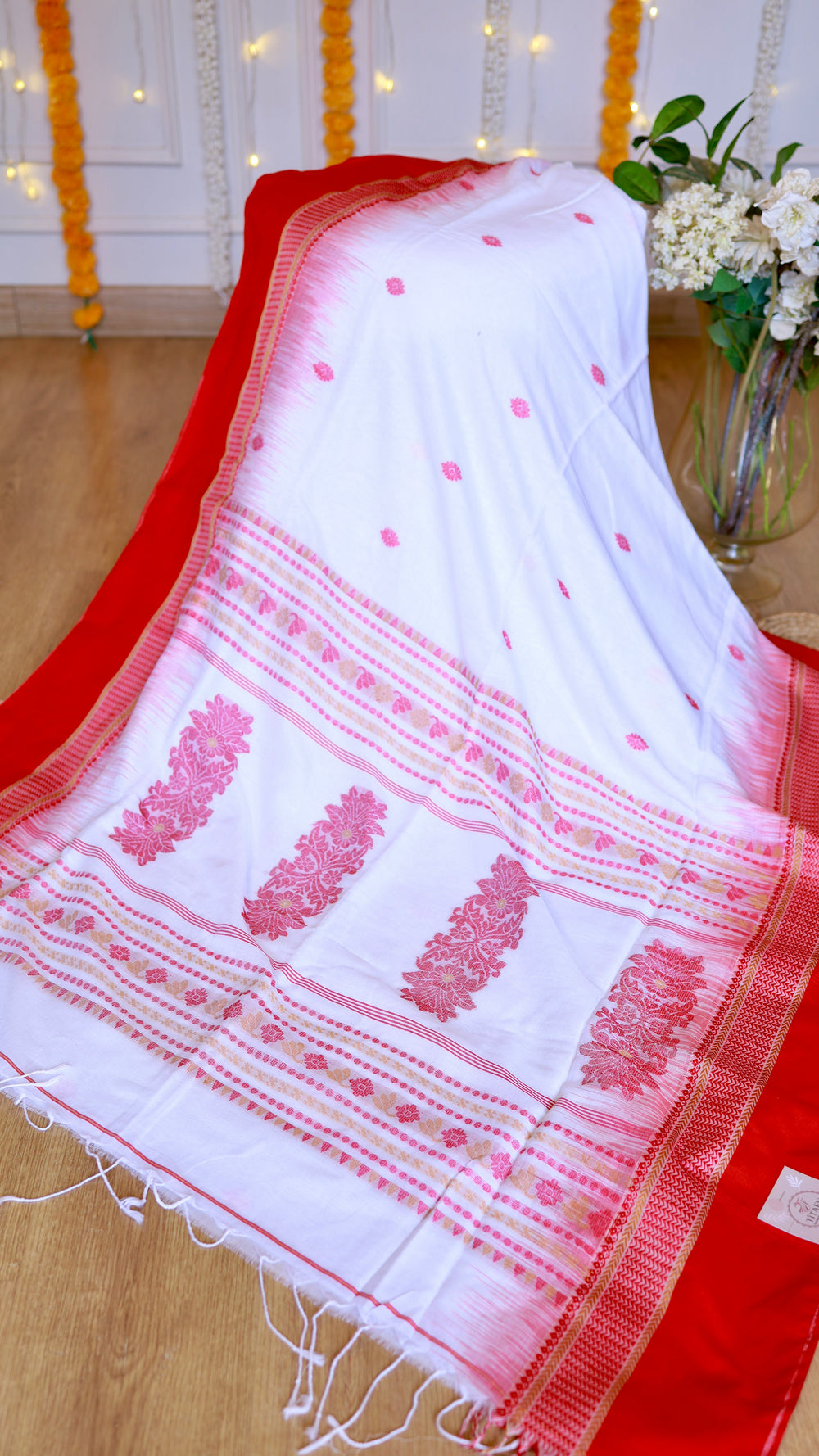 Detailed view of the woven pink Bomkai extra-weft pallu motifs, temple border, and hand-tied white tassel fringe