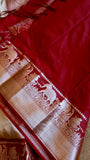 Detail shot of the contrast crimson blouse piece and saree border featuring zari woven elephant and peacock motifs.