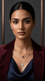 Woman wearing a maroon blazer and blue top with layered necklaces against a dark background