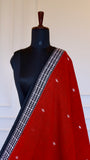 Close-up of the black border on the red Dhonekhali saree highlighting the intricate white geometric hand-thread embroidery.