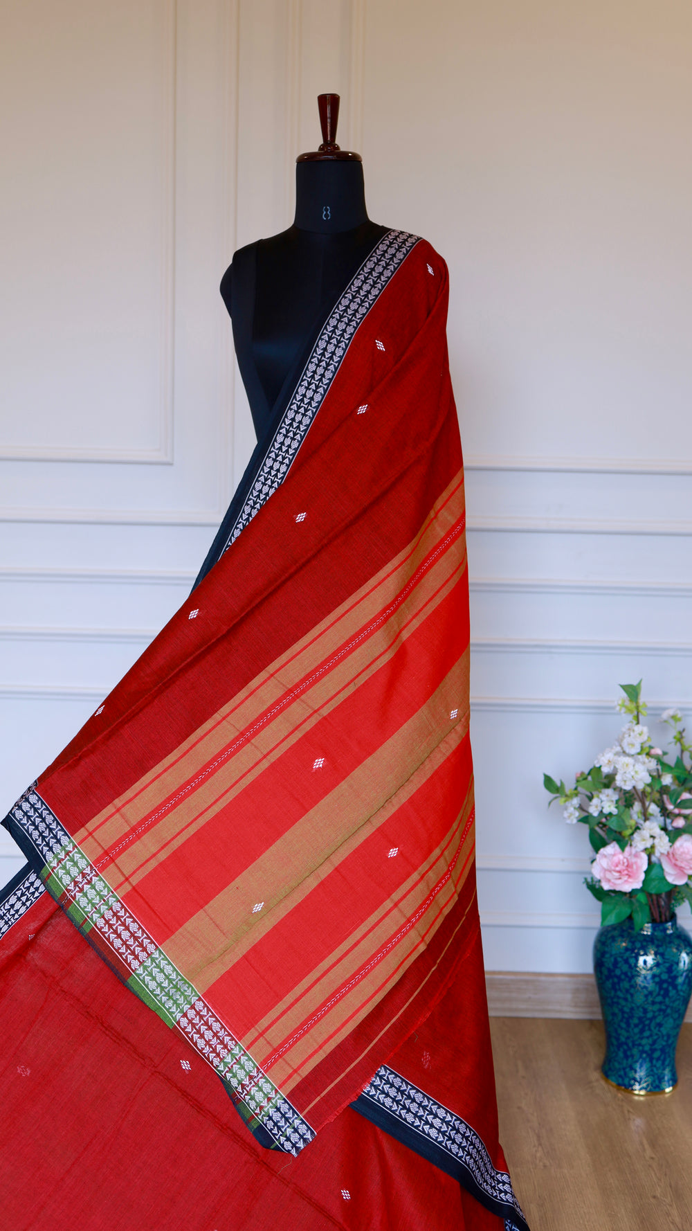 Detailed view of the Dhonekhali saree pallu featuring ochre and gold horizontal stripes against the red handloom base.