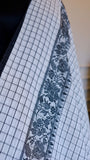 Close-up of the intricate black floral thread work border on a white
cotton saree.