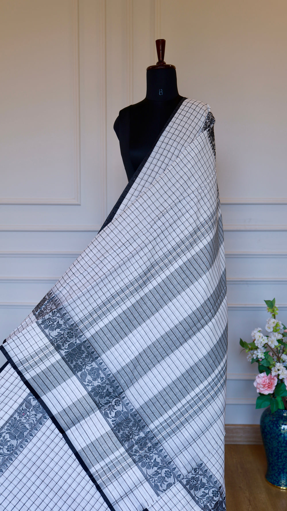Full drape of a white and black checked Dhonekhali handloom cotton
saree on a mannequin.