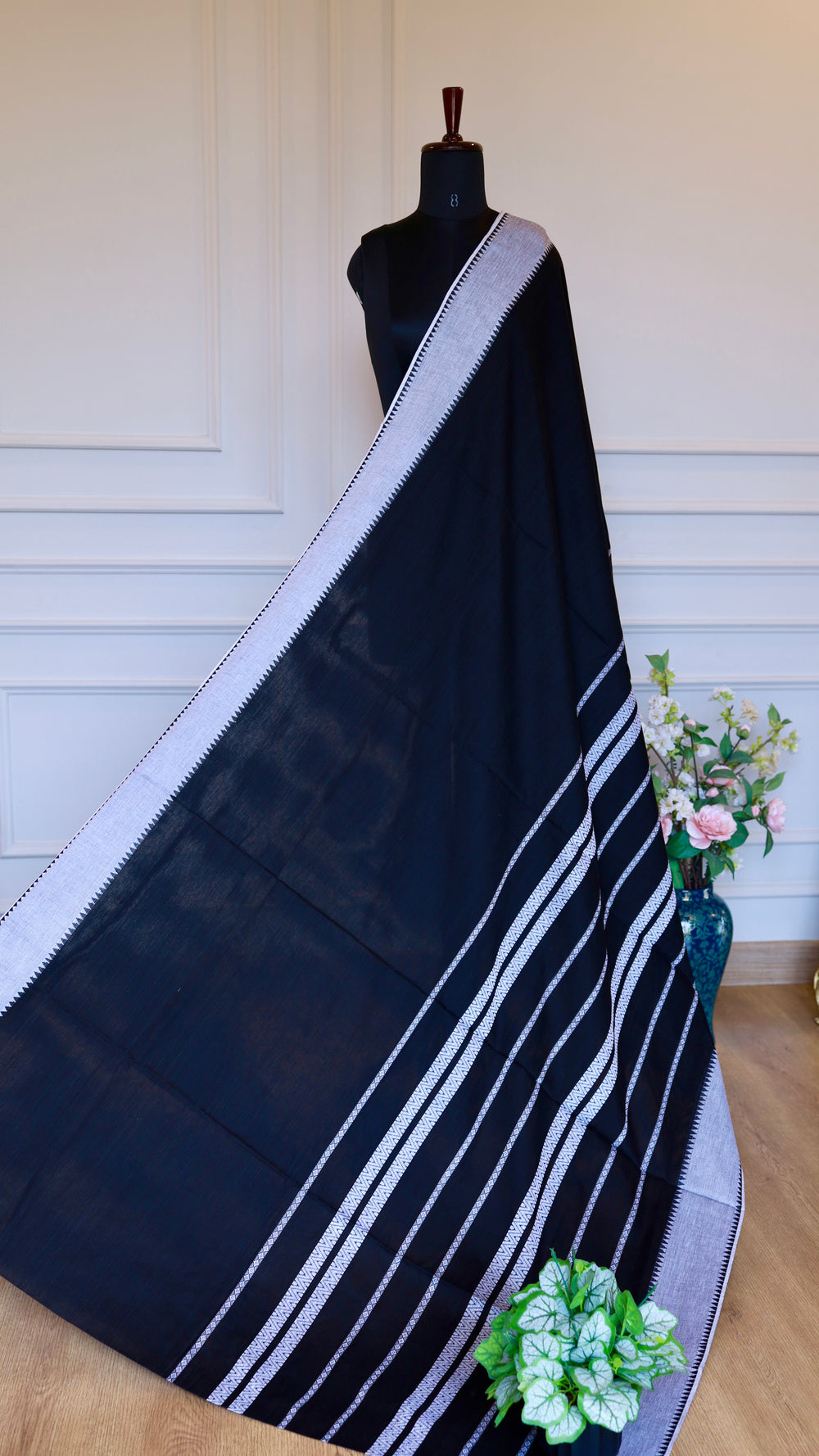Full-length view of the Dhonekhali saree draped on a mannequin, highlighting the striped white pallu and elegant black body.