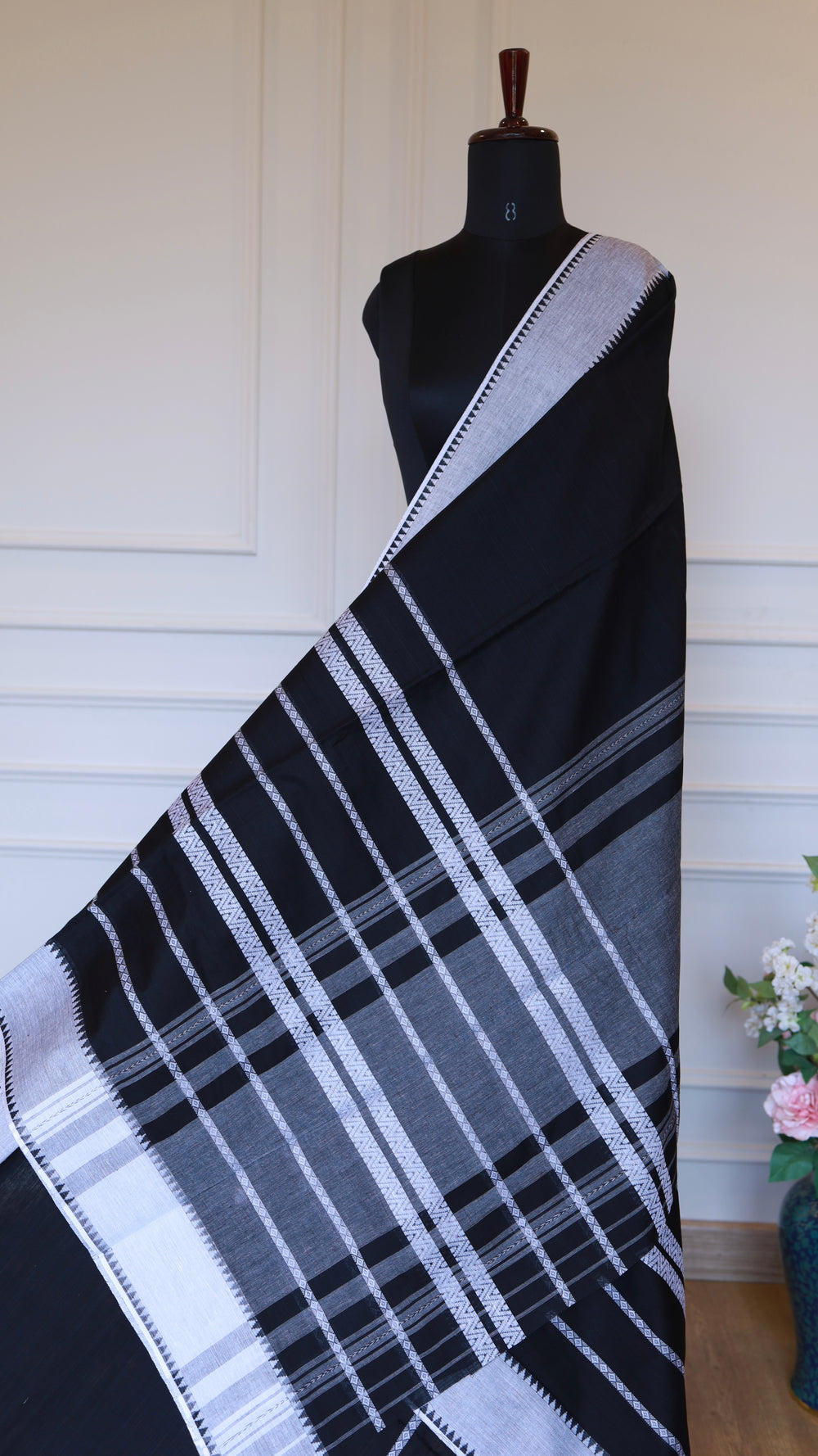 Detailed shot of the intricate white geometric thread work and striped patterns on the Black Dhonekhali saree fabric.