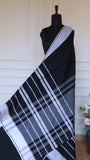 Detailed shot of the intricate white geometric thread work and striped patterns on the Black Dhonekhali saree fabric.