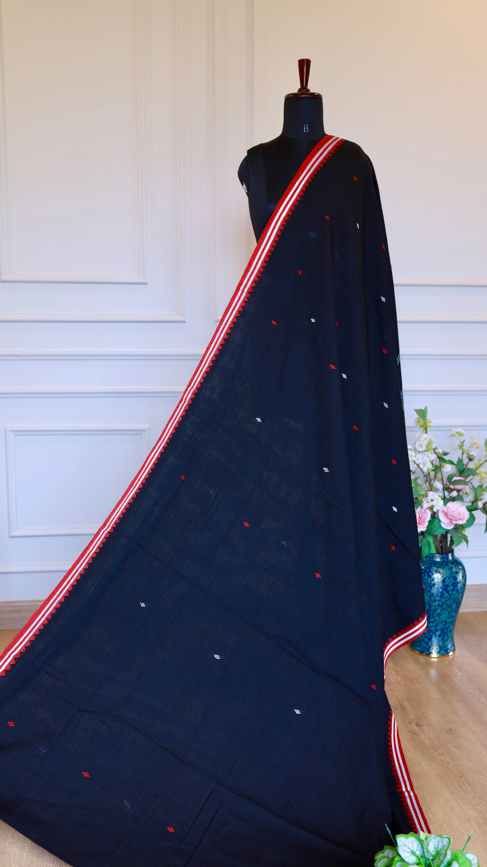 Full drape of Black Dhonekhali Saree on a mannequin showcasing the elegant fall and red temple border design