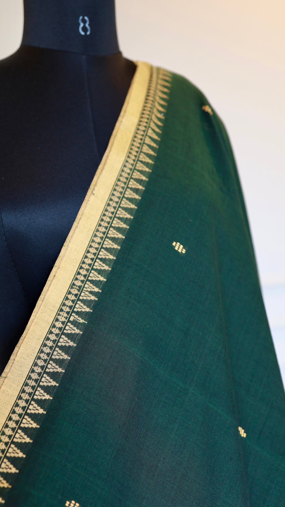 Close-up of the hand-woven thread butis and intricate border craftsmanship on the green handloom cotton fabric