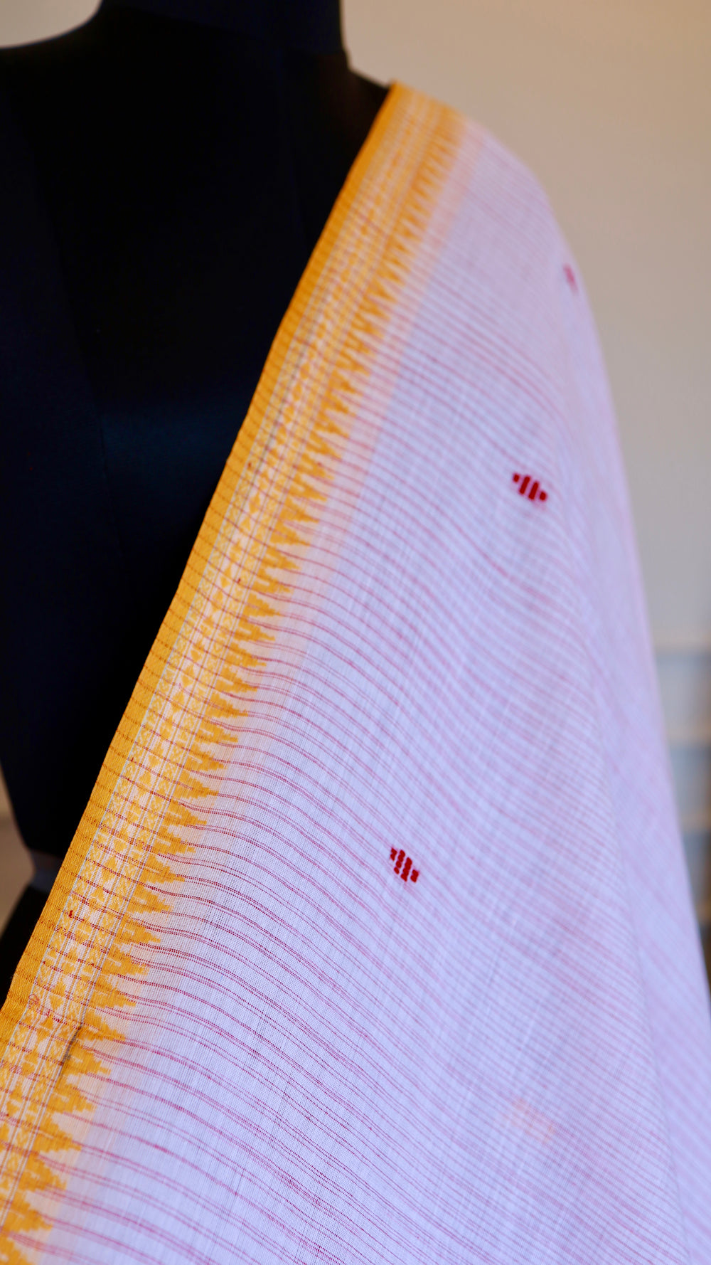 Close-up of mustard temple border on a white Dhonekhali handloom cotton saree.