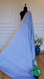 Side profile of hand-woven Dhonekhali cotton saree showing the elegant fall and scattered yellow thread buttis.