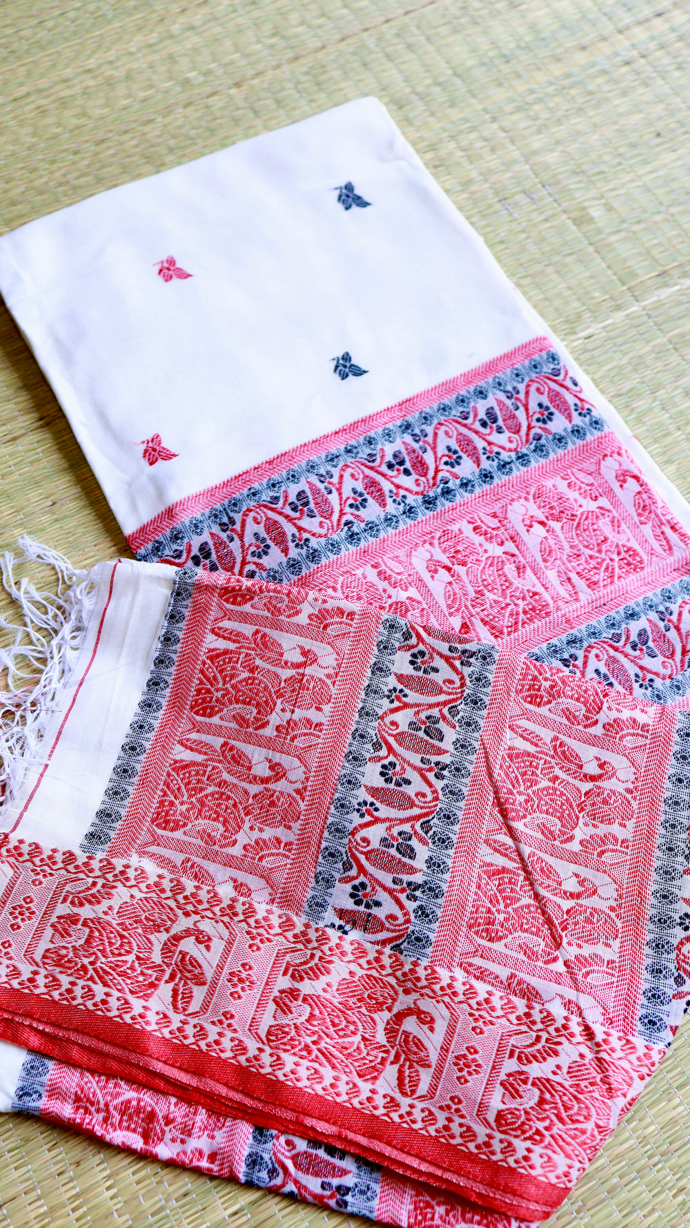 Flat lay perspective of a neatly folded off-white and red Baluchari Cotton Saree highlighting the micro motifs scattered across the body.
