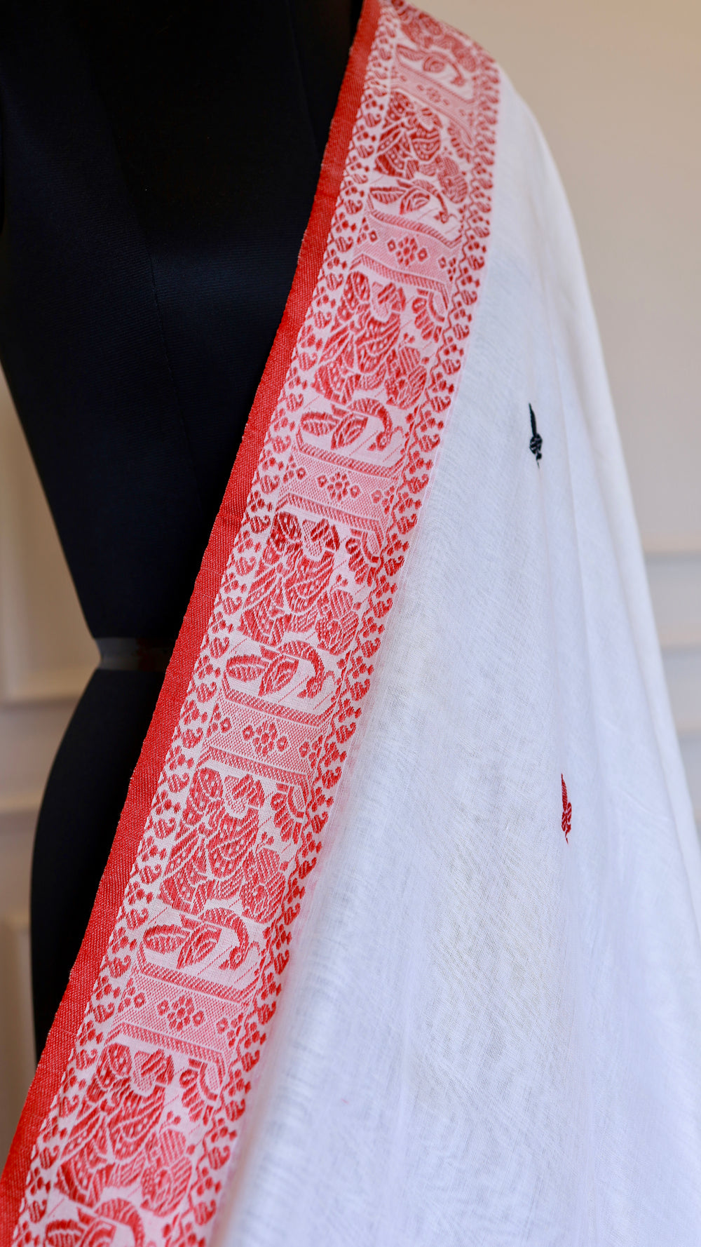 Close-up details of the red threadwork border on an off-white Baluchari Cotton Saree, showcasing the artisanal hand-knotted fringe finishes.