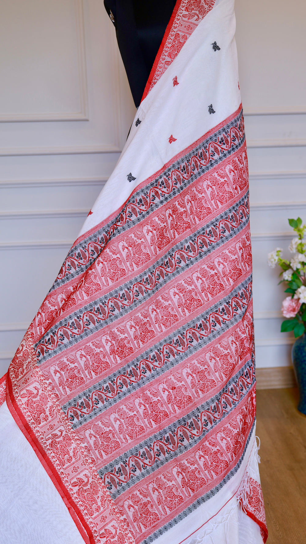 Close-up details of the red threadwork border on an off-white Baluchari Cotton Saree, showcasing the artisanal hand-knotted fringe finishes.