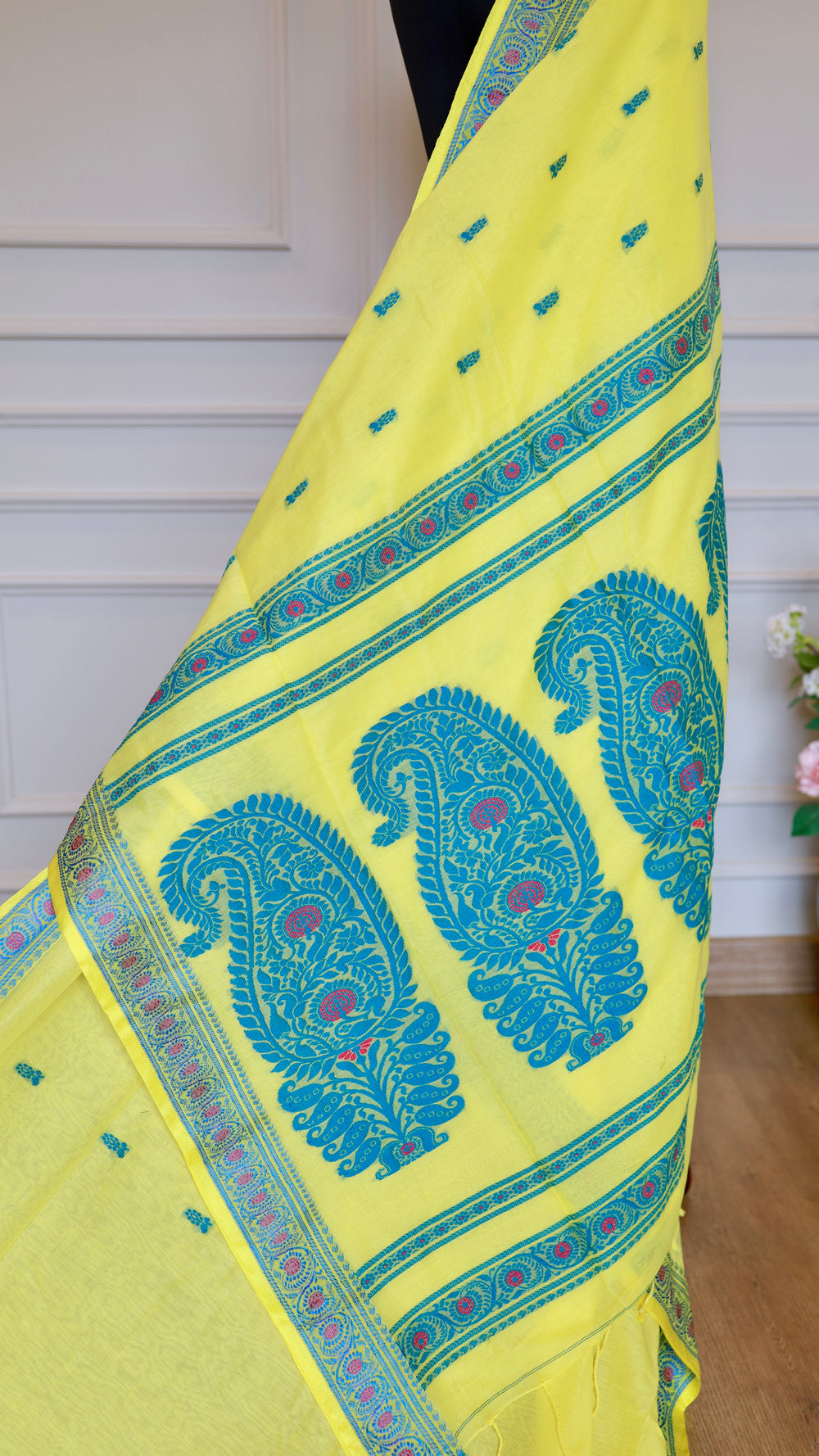 Close-up of the lemon yellow Baluchari cotton saree pallu draped vertically, highlighting the large, intricate teal blue paisley motifs and magenta pink details.