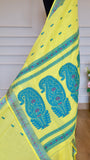 Close-up of the lemon yellow Baluchari cotton saree pallu draped vertically, highlighting the large, intricate teal blue paisley motifs and magenta pink details.