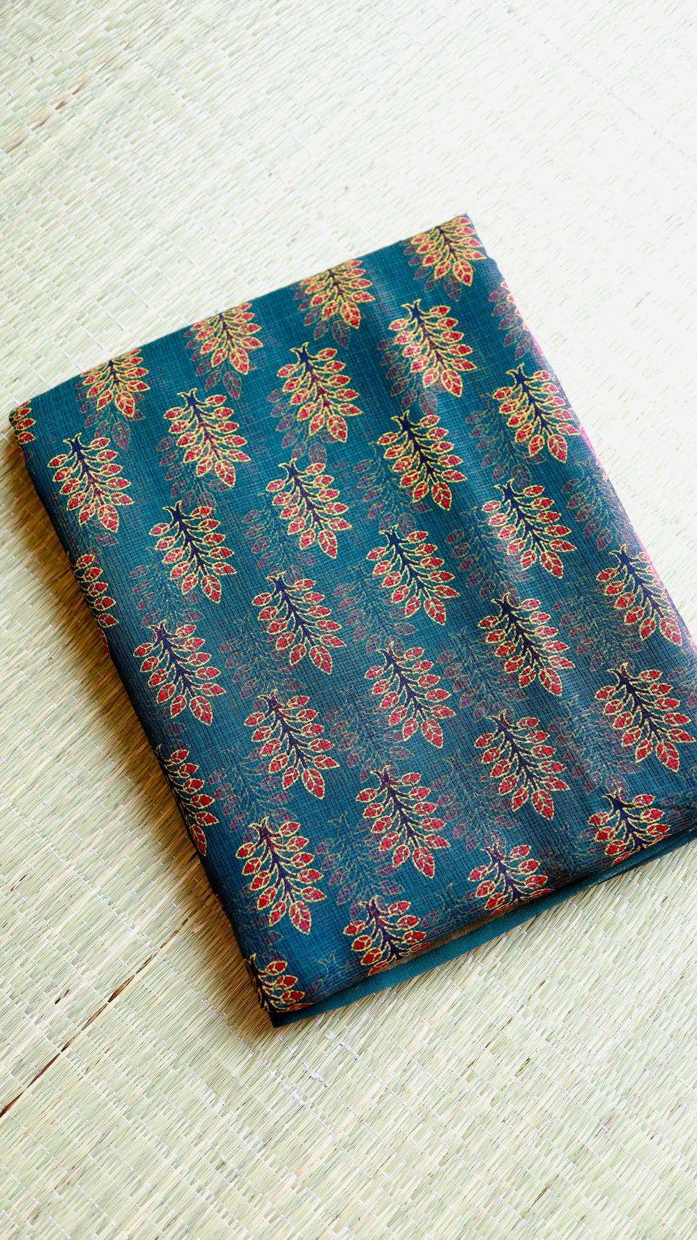 Flat-lay fold of the unstitched matching pure cotton blouse piece and body fabric of the Bagru printed Kota Doria saree on a traditional woven mat.
