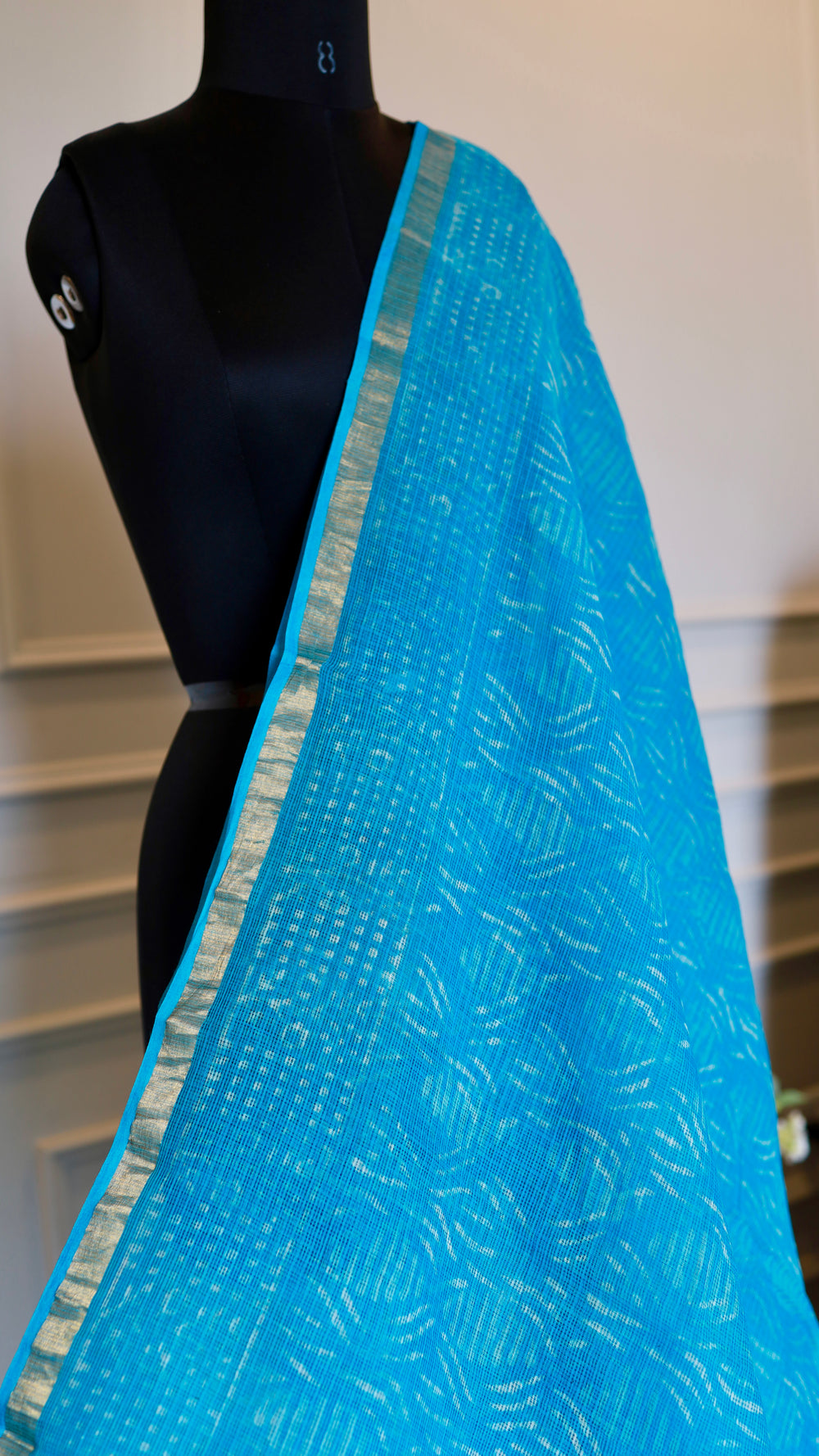 Macro shot of the premium sky blue cotton fabric showcasing the intricate geometric Bagru handblock print variations next to the golden Zari trim.