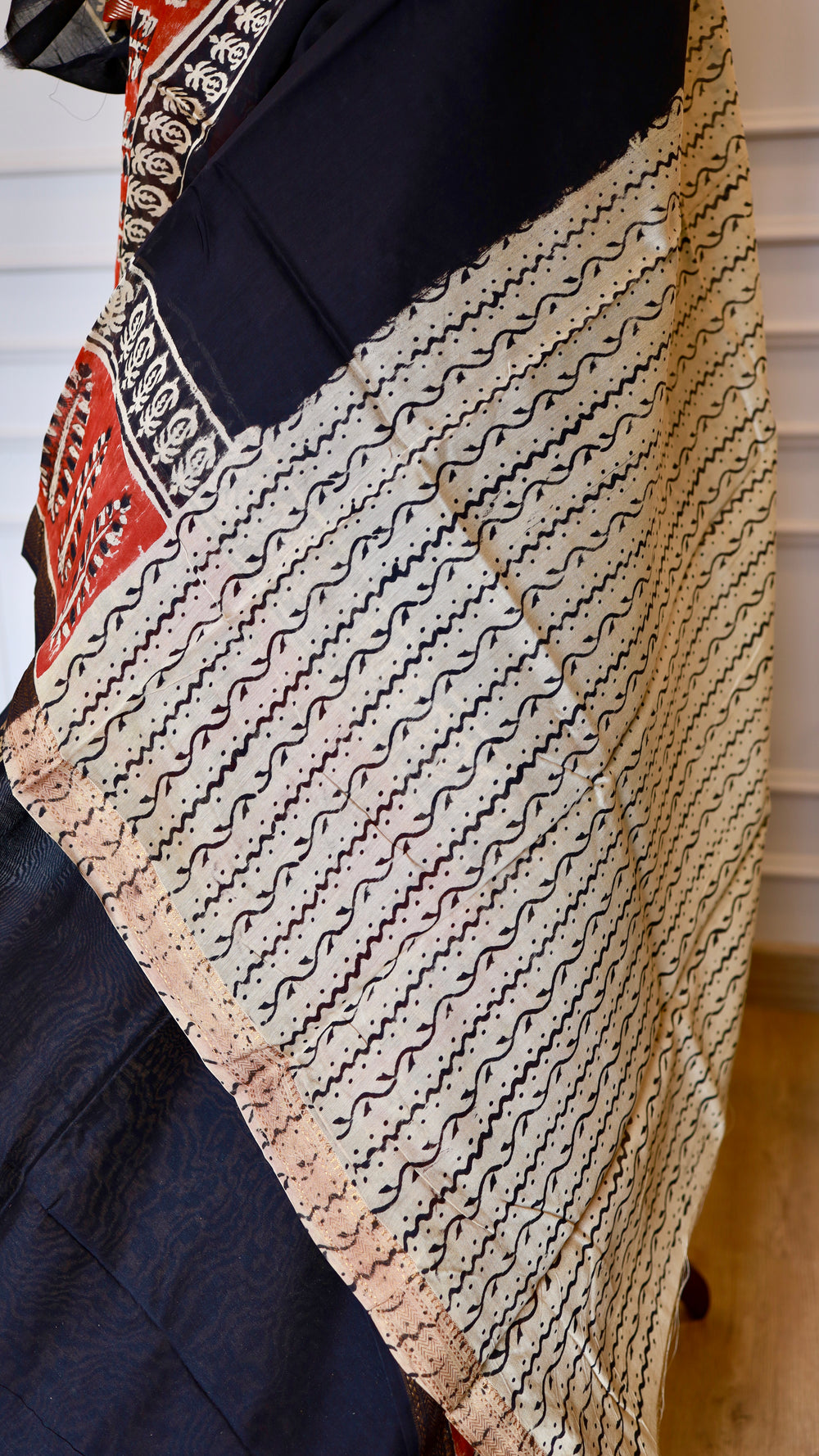 Off white blouse fabric with black wavy block prints draped next to a black Hand Block Printed Maheshwari Silk Saree.