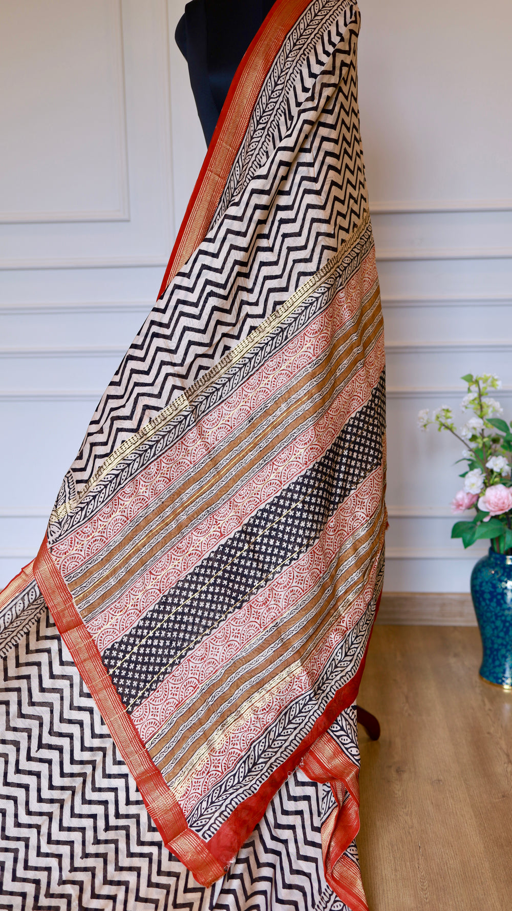 Full-length view of the elegant pallu of the Handblock Printed Maheshwari Silk Saree, highlighting the intricate red geometric blocks, horizontal gold zari bands, and its fluid, premium drape.
