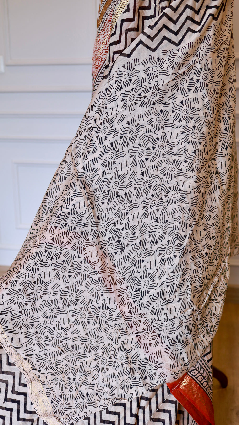 Detailed view of the lower half of the Maheshwari Silk Saree, showcasing a contrasting cream and black circular sunburst handblock print pattern layered against the chevron body.