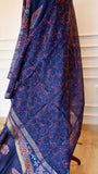 Close up texture of an indigo blue Maheshwari handblock printed silk saree showing rust orange crescent patterns and fine woven gold zari border.