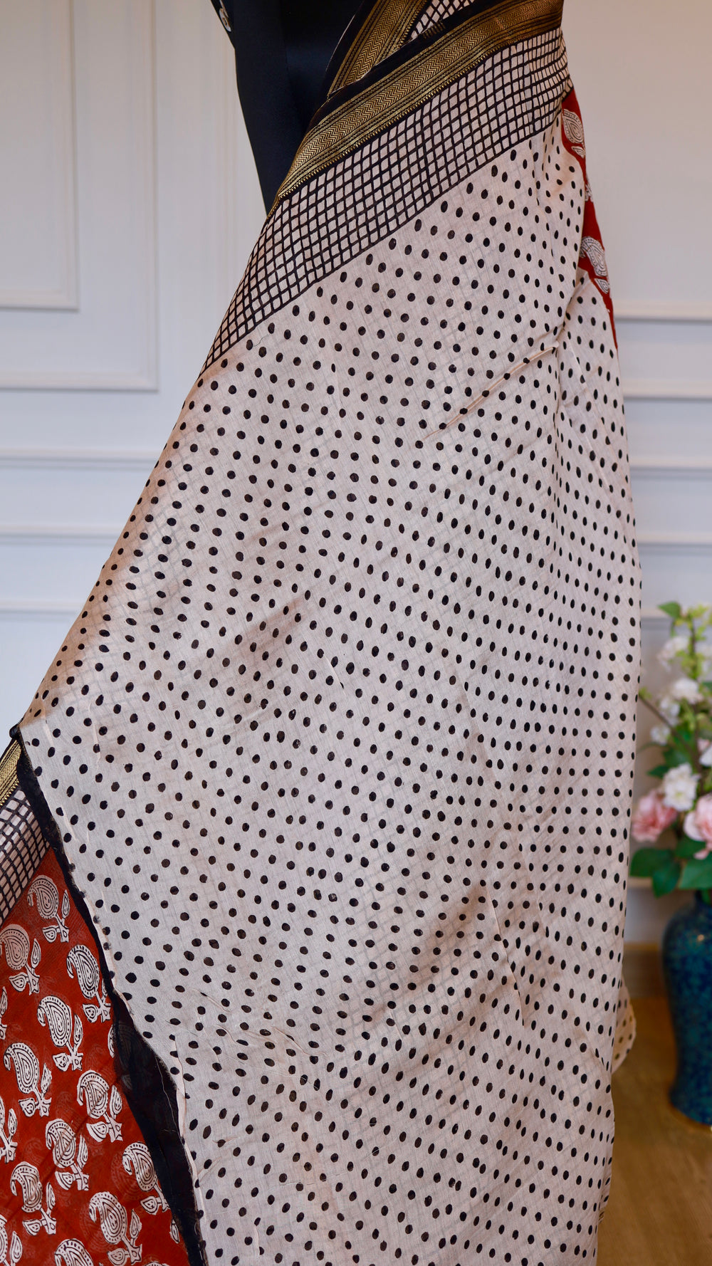 Close-up of cream body with black polka dots on a Maheshwari handblock printed silk saree with gold zari border.